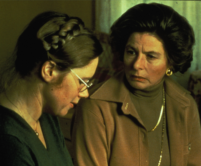 An older woman stares at a younger woman looks down