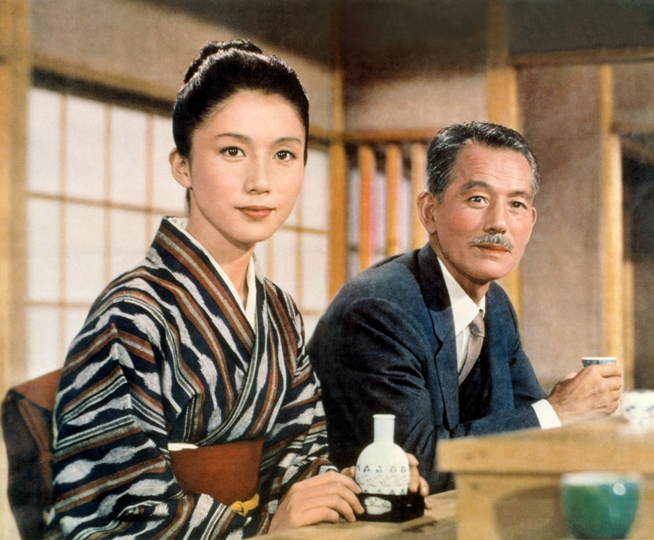 a woman in a kimono and a man in a suit sit in a restaurant