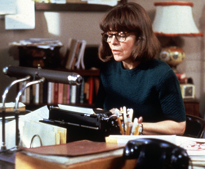 a woman with short brown hair and glasses is using a typewriter