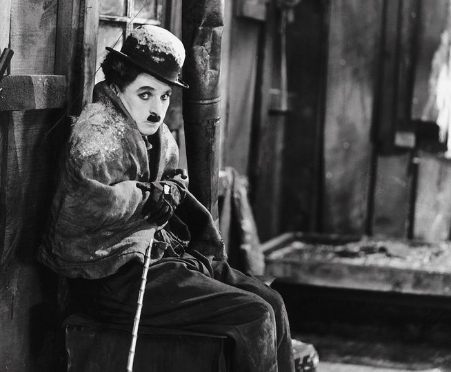a man huddling in a cabin with snow on his shoulders