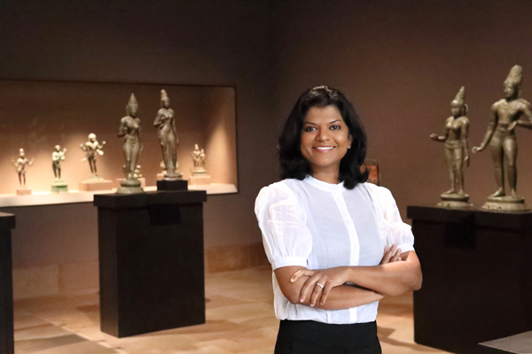 Assistant Curator Lakshika Senarath Gamage Assistant Curator Lakshika Senarath Gamage posed with her arms folder standing in the center of an asian art gallery with a white blouse and black pants