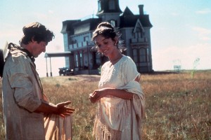 color film still of a man and a woman in a field with a house behind them