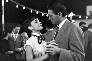 a woman and man looking at each other as they dance outdoors