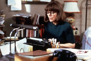 a woman with short brown hair sits at at a desk typing