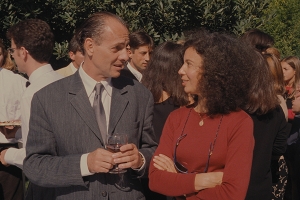 a man wearing a gray suit and a woman with a red sweater stare at each other